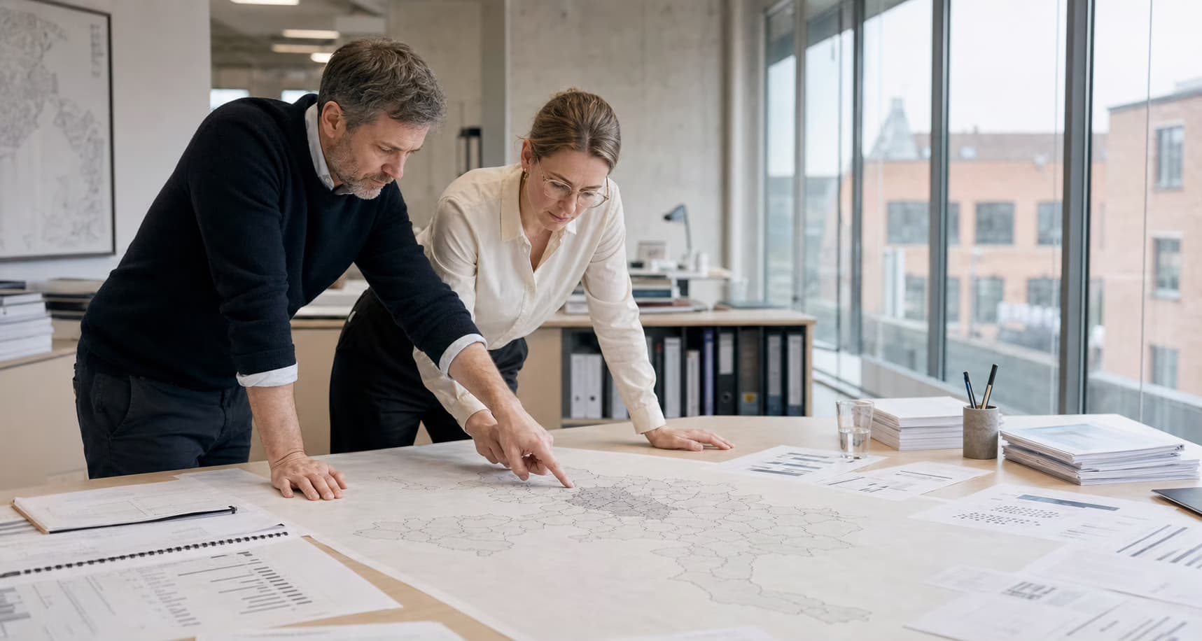 To analytikere arbejder med et papirkort over danske kommuner
